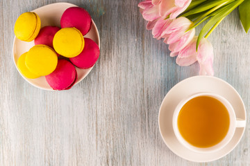 macaroons, tea and a bouquet of tulips on a rustic wooden background, copy space - congratulation for St. Valentine's Day