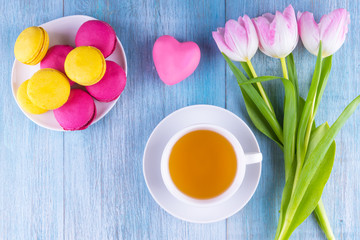 Fototapeta na wymiar macaroons, tea and a bouquet of tulips on a rustic wooden background, copy space - congratulation for St. Valentine's Day