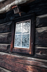 Fototapeta na wymiar Rustic house with snowflakes on window