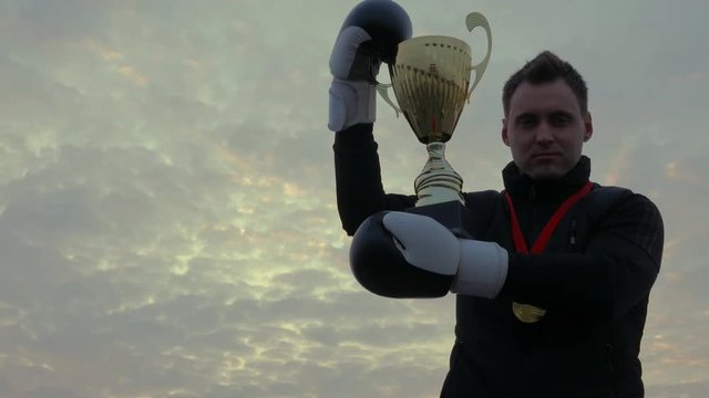 Boxer in the gloves kissing his winner gold cup