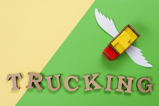 Abstract picture of a truck with wings and a word of trucking. Green background. Cargo transportation of the future