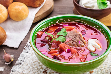 Bowl of borscht on table. Sour soup with beetroots, cabbage and beef. Traditional Russian and Ukrainian dish. 
