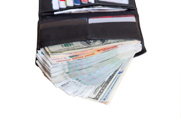 Black leather wallet with lots of cash, rubles and dollars. Rich in purse on white background lies open, blurry plastic cards in the background
