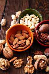 bowls with mixed nuts on wooden background. Healthy food and snack. Walnut, pecan, almonds, hazelnuts and cashews.