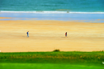 Fototapeta na wymiar Two walkers on the beach miniature tilt shift view