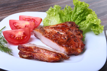grilled pork chops with tomato, leaves lettuce and ketchup on plate.