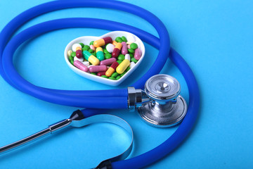 Stethoscope, RX prescription and colorful assortment pills and capsules on plate.
