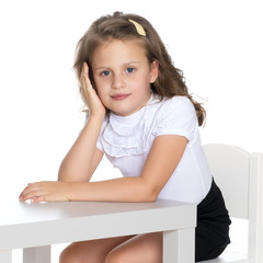 Little girl is sitting at the table