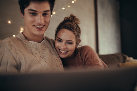 Hygge couple sitting on sofa with a laptop