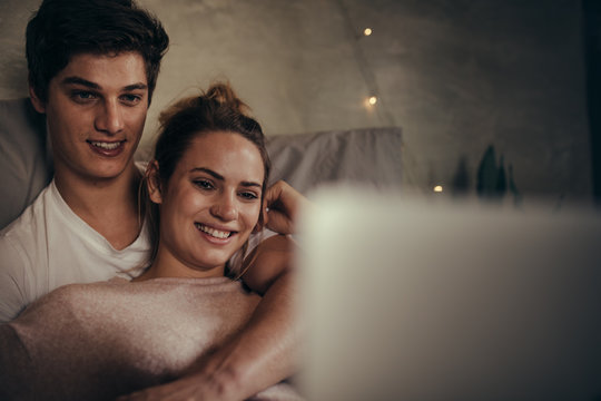 Hygge couple watching video on laptop in bedroom