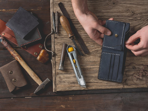 Working Process Of The Leather Bag Or Messenger In The Leather Workshop. Master Craftsman Hands On The Table Background. Color Tone Image. View From Above.