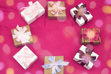 Gift boxes tied with satin coloured ribbon on a pink background.