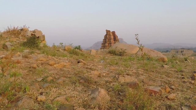 Ancient Hindu temple ruins. Smooth tracking shot along ground to hill overlooking huge Vittala temple complex in Hampi, Karnataka, India. 2X slow motion.