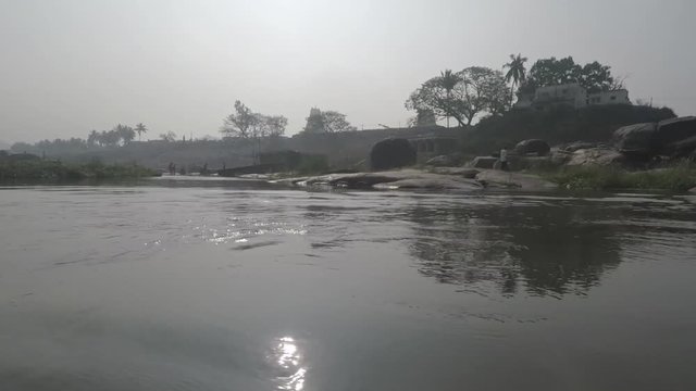 Crossing river in Hampi, India. Smooth shot passes Shiva lingams in water, islands, grass, and men bathing an elephant. 2X slow motion.
