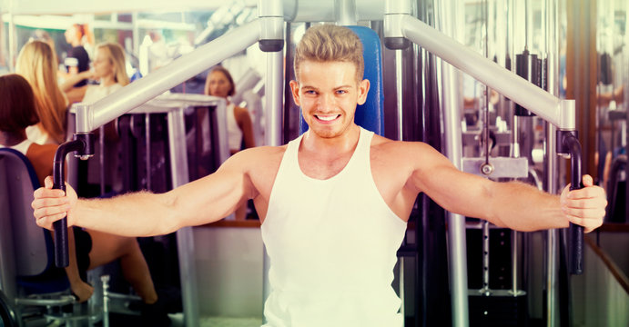 Young man using fly machine in gym.