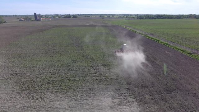 aerial tractor discing field fly through dust 4k