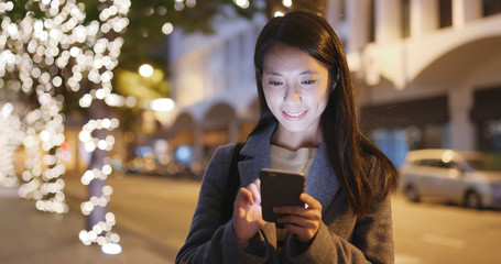 Businesswoman use of mobile phone in city at night