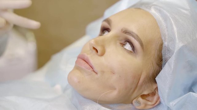 doctor dermatologist changes the shape of the cheek in a woman who wants to look younger