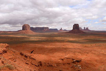 Naklejka premium Storm Cloud Over Red Valley - The sun shines through thick spring stormy clouds onto the red desert floor of the Monument Valley, Utah & Arizona, USA.
