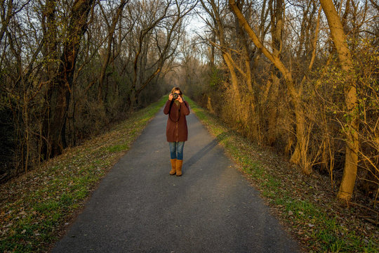 woman standing on forest trail taking photo