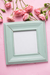 Empty photo frame and border from  pink roses flowers on  pink textured background.