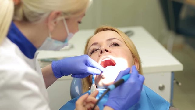 Woman whiten teeth at the dentist. Young female sitting in dentist office and smile.