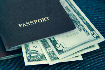 Dollars in the black passport on a blue textile background