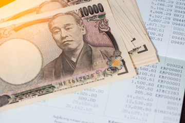 Business, finance, investment or accounting concept : Japanese money banknoter and saving account book or financial statement
