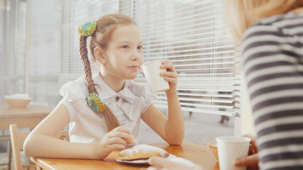Fototapeta premium Little girl with mommy in cafe - teen explains something for mother
