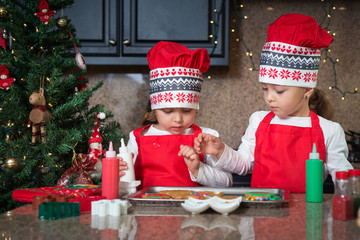 Twin girls in red making Christmas cookies