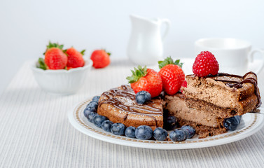 Big chocolate cheesecake with blueberry strawberry raspberry on a round plate.