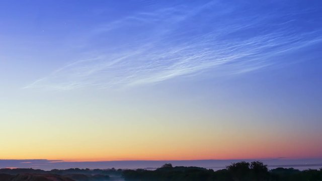 noctilucent clouds NLC with filament gravity wave structure in summer morning twilight timelapse