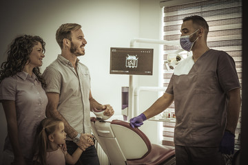 Little girl with parents at dentist.