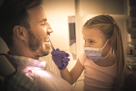 Little girl and father playing in dentist office.
