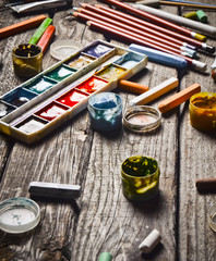 A group of products for drawing and creativity on a wooden table. Rustic style. Gouache, oil painting, watercolor paints, crayons, pencils.