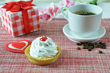 Gift or present box with red bow ribbon and heart for Valentines day. a cup of coffee. a beautiful cake with cream cherries. capcake