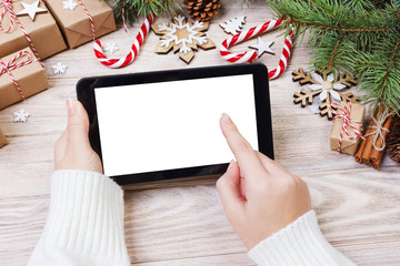 Christmas background: female hands uses opened tablet with copy space on rustic wooden table...