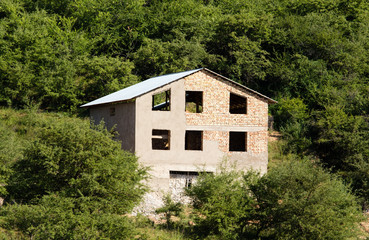 Fototapeta na wymiar Unfinished house on a mountainside with trees
