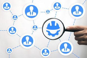 Business Industrial Search Development Company Strategy Teamwork concept. Hand holds a magnifying glass with hard hat gear icon on a virtual interface.
