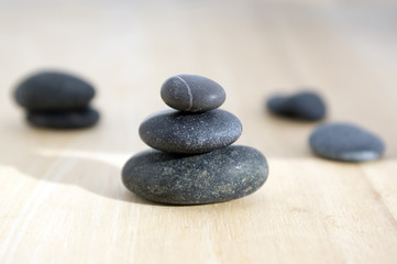 Fototapeta na wymiar Harmony and balance, poise stones on wooden table, black pebbles in sunlight