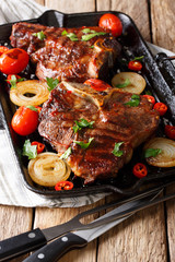 Tasty barbecue: T Bone steak with tomato, chili and onions on the grill pan close-up. vertical