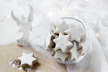 Cookies Cinnamon star in a glass vase on a white background decorated with a figurine of an angel and a garland.