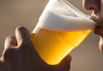 Fresh beer in a plastic cup in the hand