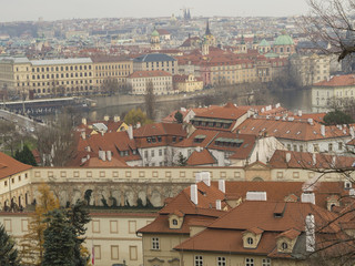 Fototapeta na wymiar Prague city panorama View on old town with teen saint nicholas church palaces and vltava river bank from old castle steps way to prague castle in winter evening