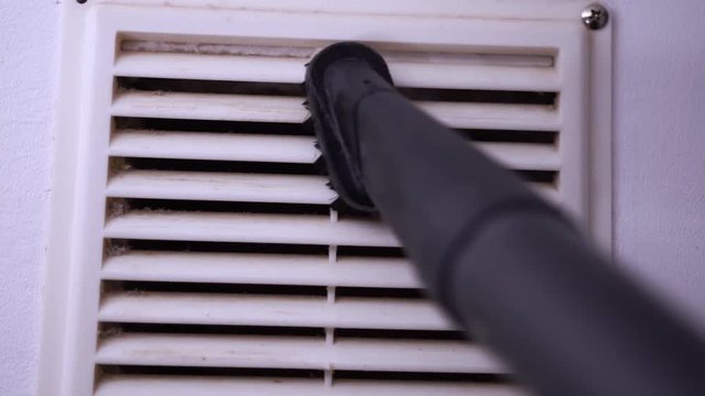 Closeup of Cleaning Ventilation Grill with Vacuum Cleaner Pipe. Housework and Cleaning Concept.