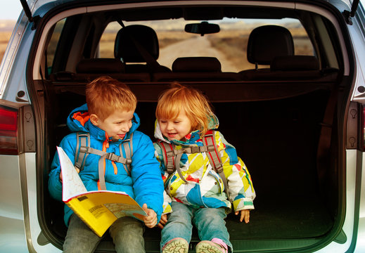 little boy and girl looking at map while travel by car