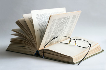 opened book, lying on the bookshelf with a glasses