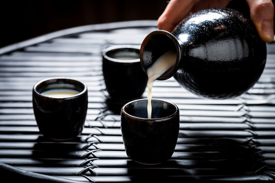Pouring sake in to black ceramics on black table