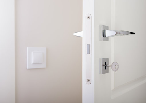 Closeup of white interior doors. Lock with key and chrome door handle