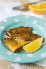 Crepe suzette in caramel sauce on a plate with a slice of orange. French dessert.